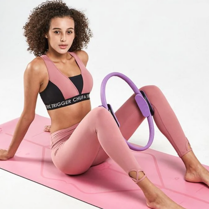 Frau in rosa Sportbekleidung mit Pilates-Ring auf rosa Yogamatte, Fitness, Workout.