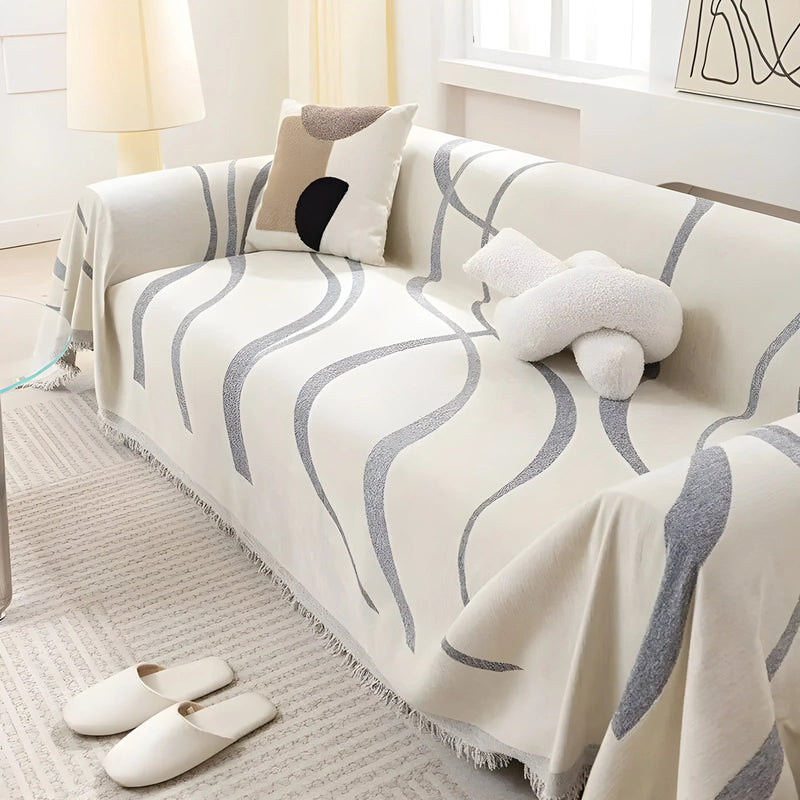 Beige Sofaüberwurf mit grauem Wellenmuster, dekoratives Kissen, modernes Wohnzimmerdesign.