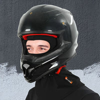 Schwarzer Carbon-Motorradhelm mit Visier, getragen von Person, auf grauem Hintergrund.