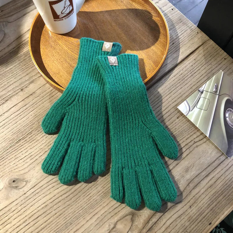 Grüne Strickhandschuhe aus Wolle auf Holztisch, ideal für Wintermode und Outdoor-Aktivitäten.