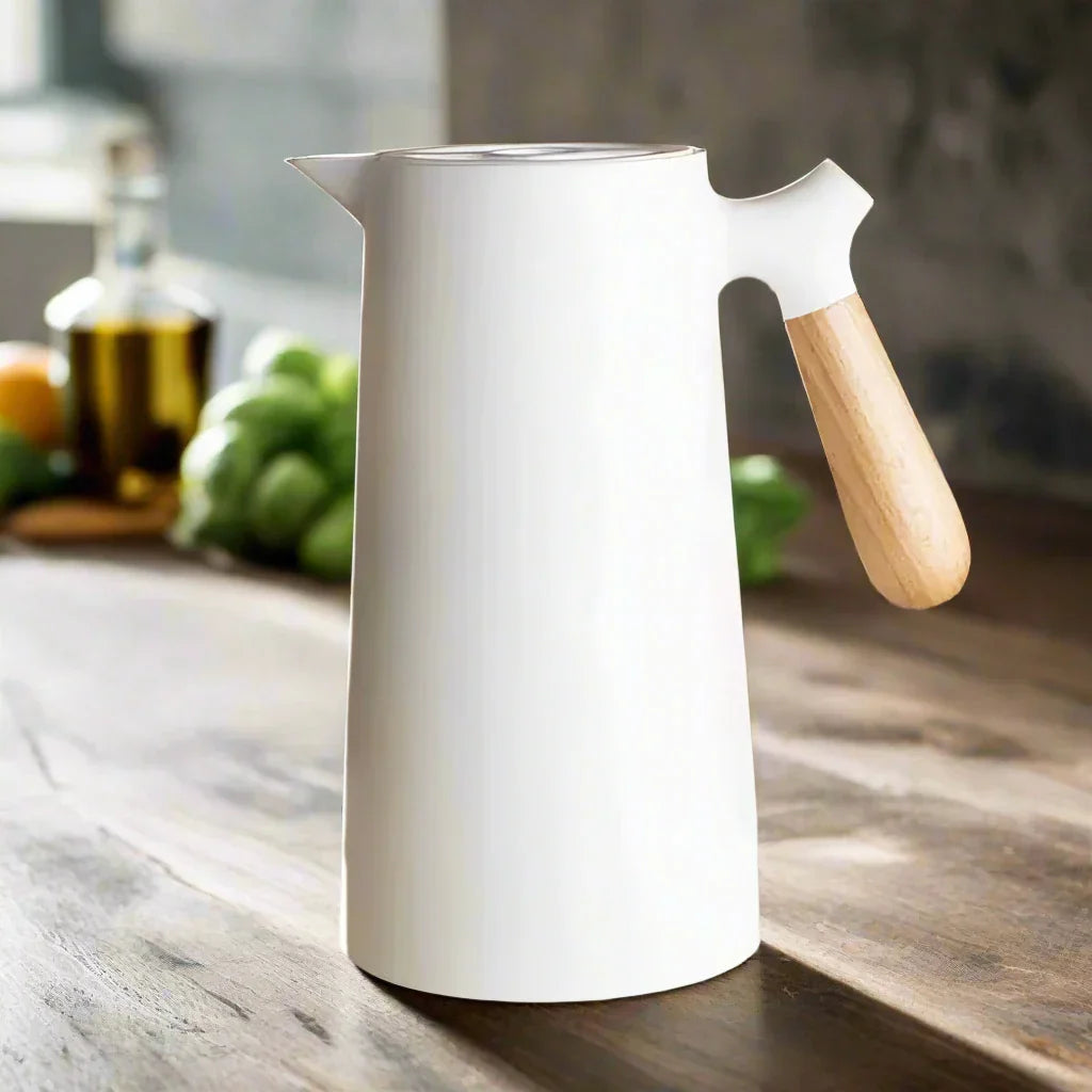 Weiße nordische Thermoskanne mit Holzgriff auf Holztisch, stilvolles Küchendesign.