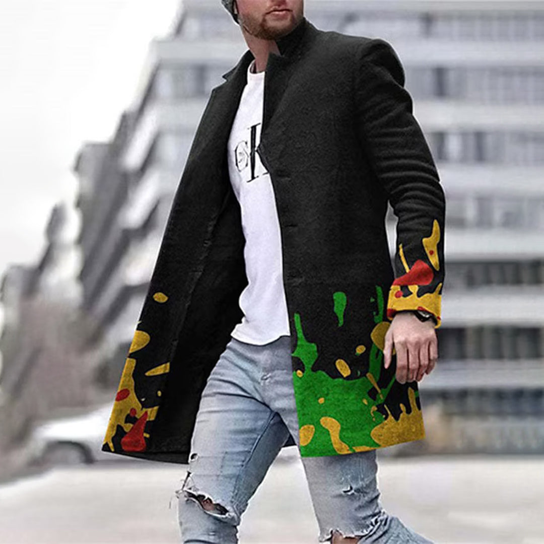 Mann in schwarzem Mantel mit buntem Muster, zerrissene Jeans, urbaner Hintergrund.