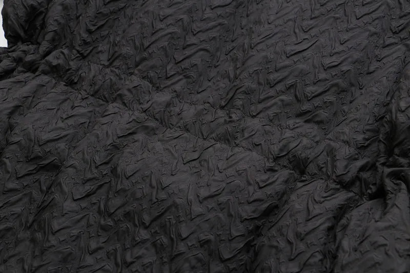 Schwarzer, strukturierter Stoff mit geprägtem Muster, ideal für Mode und Textildesign.