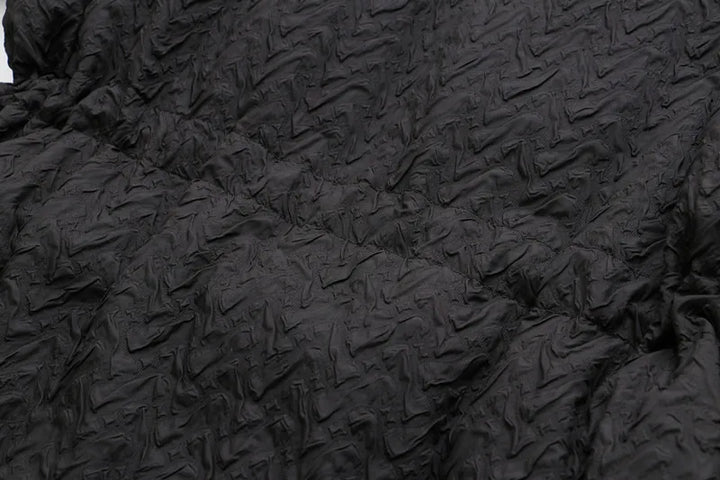 Schwarzer, strukturierter Stoff mit geprägtem Muster, ideal für Mode und Textildesign.