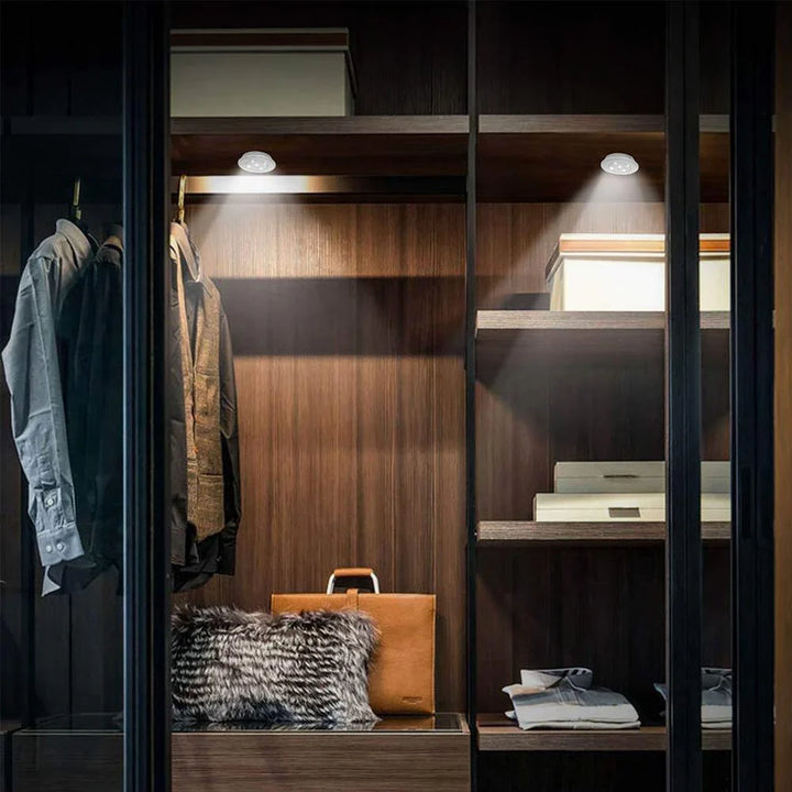 Begehbarer Kleiderschrank mit LED-Beleuchtung, Holzböden, Kleidung, Boxen, braune Ledertasche.