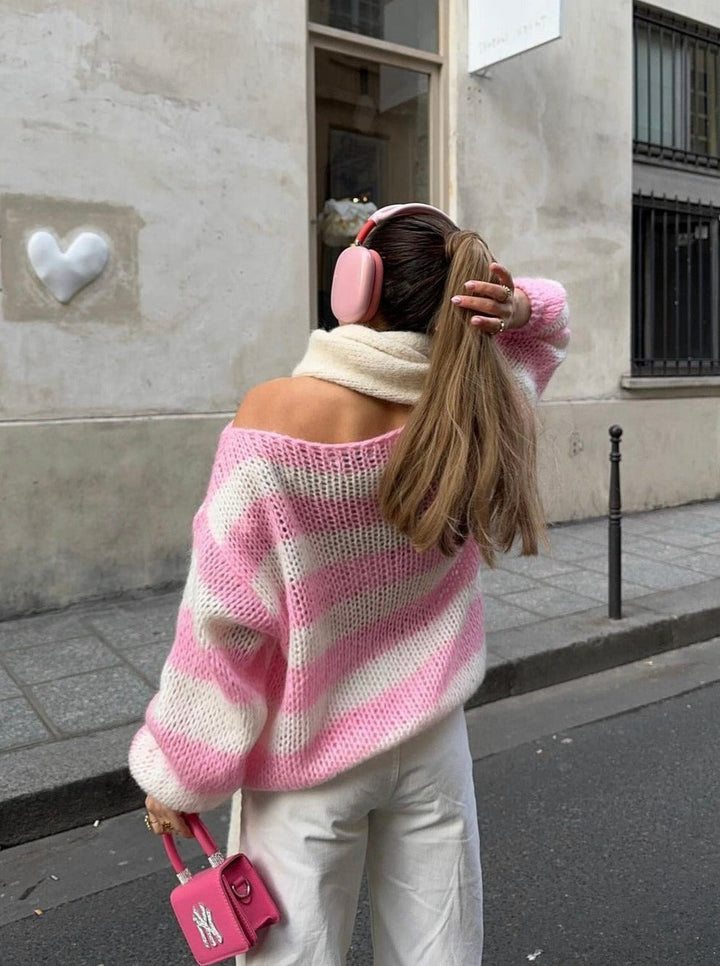 Frau in rosa-weiß gestreiftem Pullover, weiße Hose, rosa Kopfhörer, rosa Tasche, Straße.