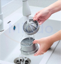 Person reinigt silberne Saftpresse unter Wasserhahn in weißem Waschbecken.