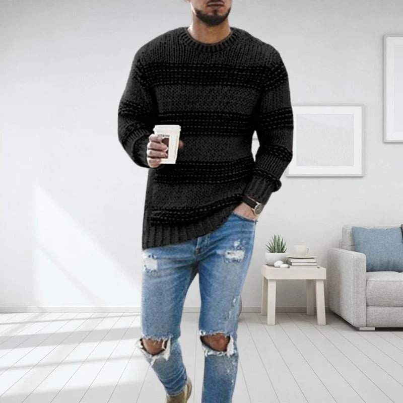 Mann in schwarzem Strickpullover, zerrissene Jeans, hält Kaffeetasse, modernes Wohnzimmer.