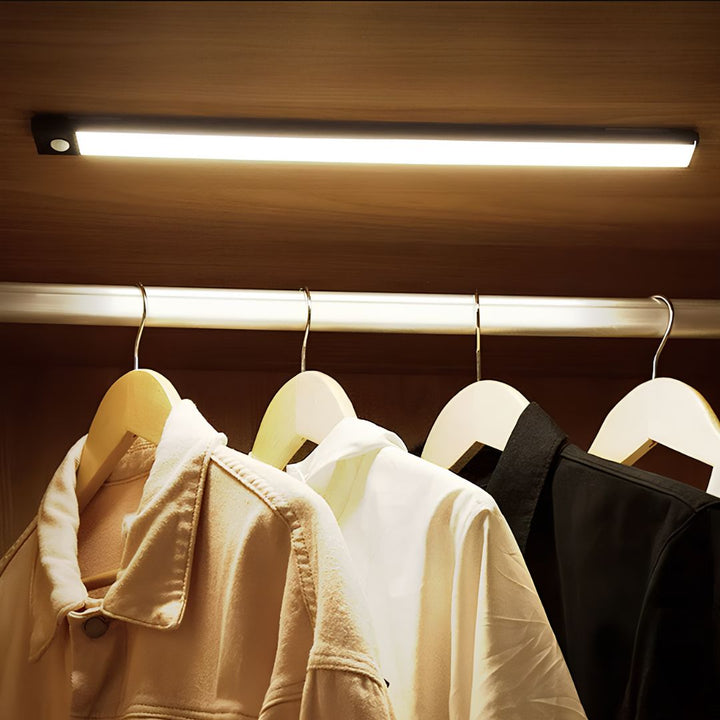 LED-Schrankleuchte beleuchtet Kleiderstange mit Jacken, energiesparend, warmweißes Licht.