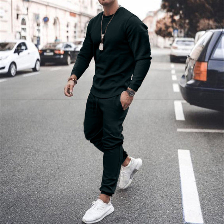Mann in schwarzem Trainingsanzug und weißen Sneakers auf Straße, urbaner Stil, Freizeitmode.