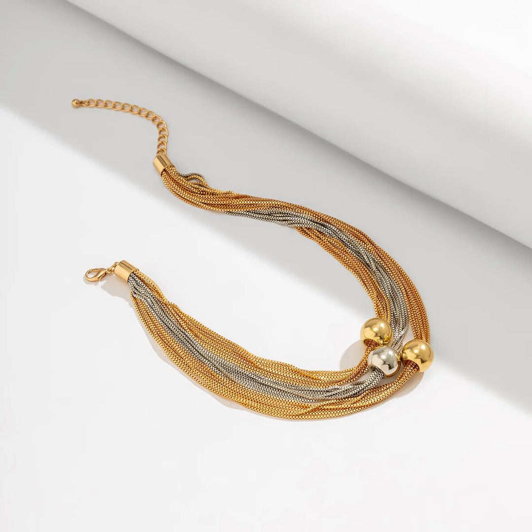 Goldenes Halskette mit mehrsträngigem Design und Kugelakzenten auf weißem Hintergrund.