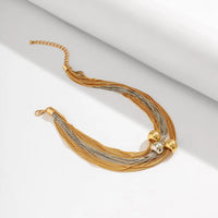 Goldenes Halskette mit mehrsträngigem Design und Kugelakzenten auf weißem Hintergrund.