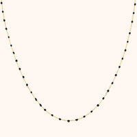 Goldene Halskette mit schwarzen Perlen, elegantes Schmuckdesign, Damenaccessoire.