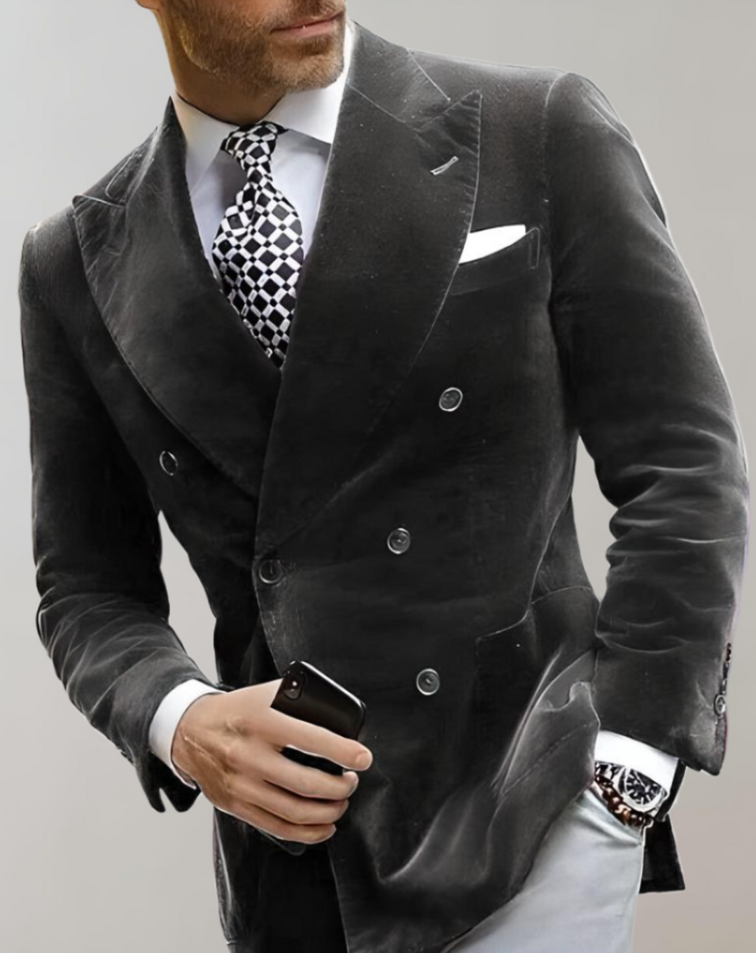 Mann im eleganten schwarzen Samtanzug mit Krawatte und Smartphone, stilvolle Herrenmode.