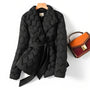 Schwarze gesteppte Damenjacke mit Gürtel, elegant, modisch, Herbst-Winter, neben brauner Handtasche.