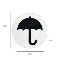 Runder Teppich mit schwarzem Regenschirm-Motiv, 40cm Durchmesser, 2cm dick, weißer Hintergrund.