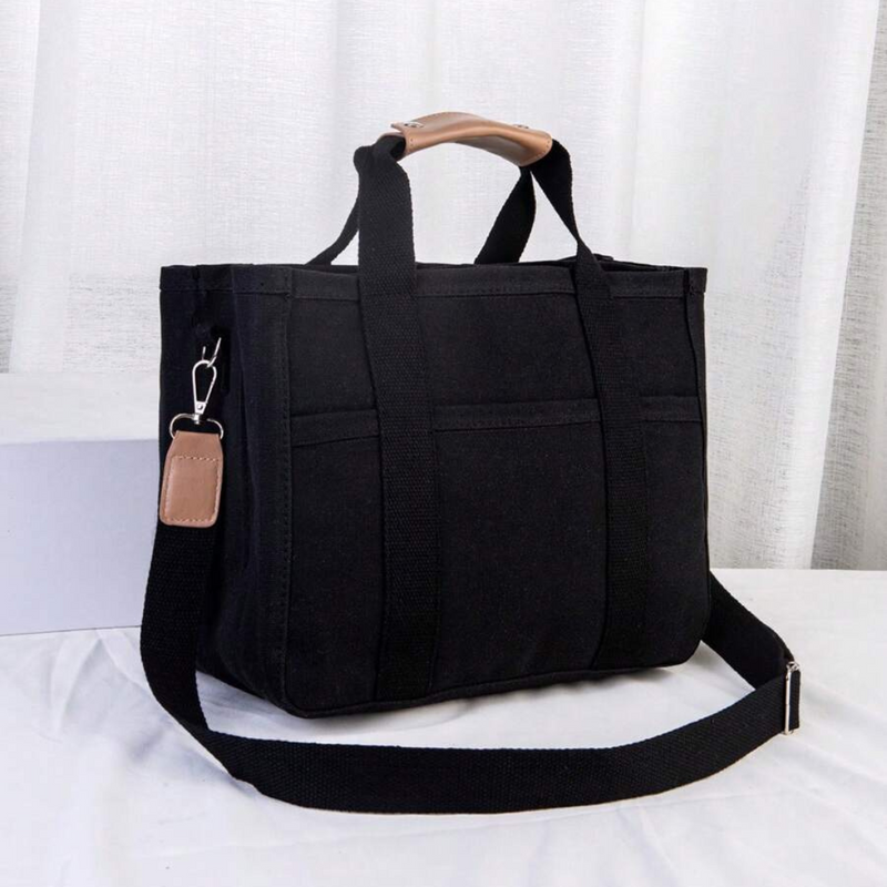 Schwarze Canvas-Tasche mit Schulterriemen, Ledergriff, ideal für Alltag und Reisen.