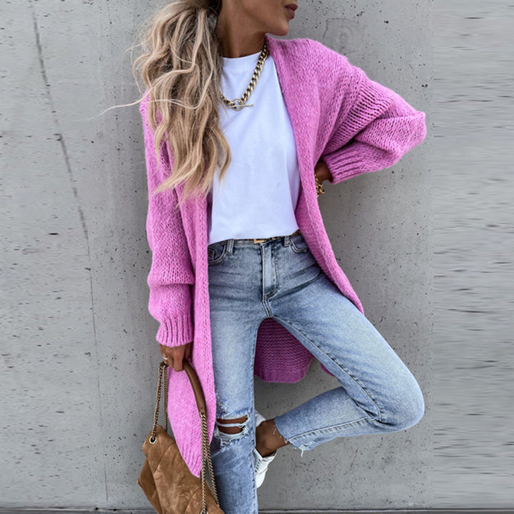 Frau in rosa Strickjacke, weiße Bluse, zerrissene Jeans, braune Tasche, lässiger Stil.