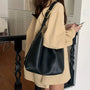 Frau mit schwarzer Ledertasche, beige Jacke, Smartphone, modernes Interieur.