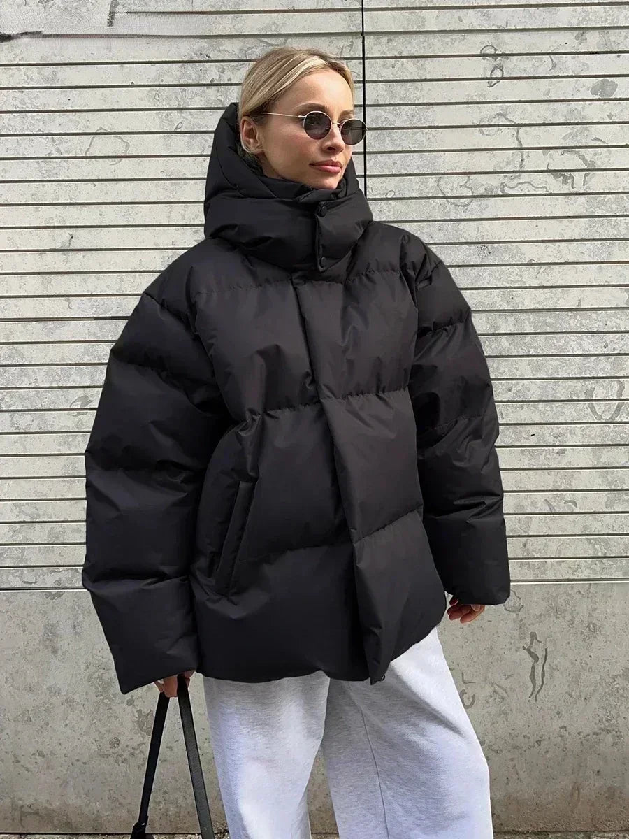 Frau in schwarzer Daunenjacke, Wintermode, stylisch, modern, Sonnenbrille, lässig, urban.
