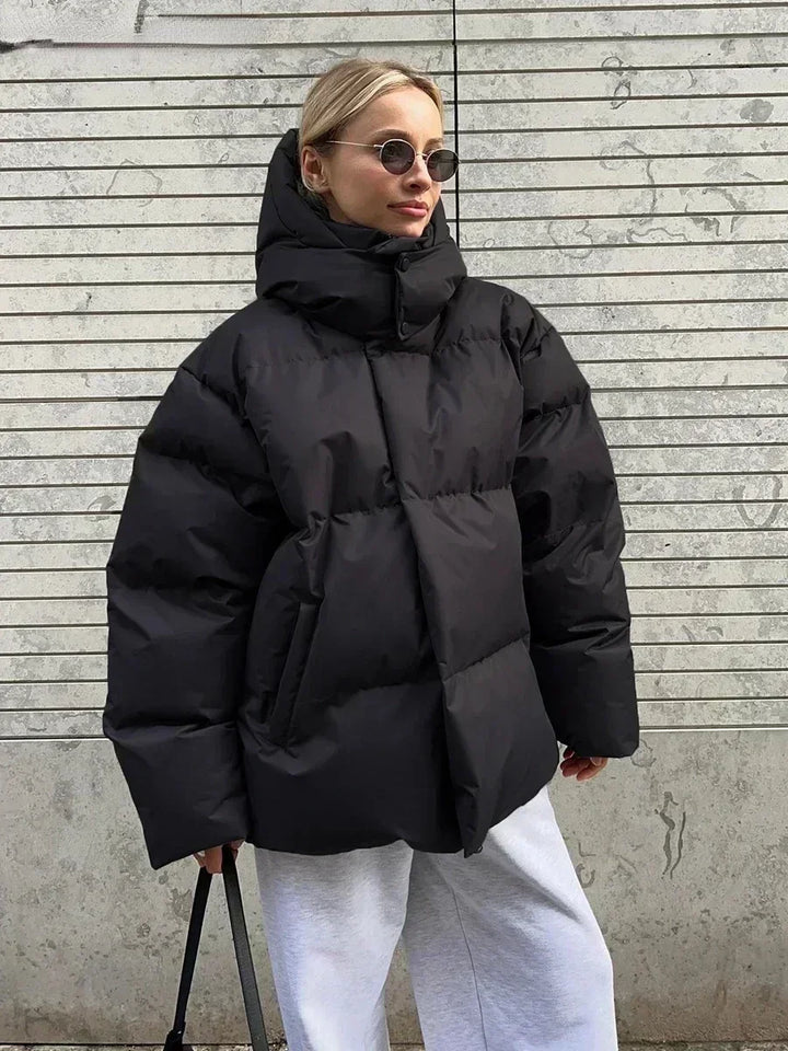 Frau in schwarzer Daunenjacke, Wintermode, stylisch, modern, Sonnenbrille, lässig, urban.