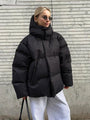 Frau in schwarzer Daunenjacke, Wintermode, stylisch, modern, Sonnenbrille, lässig, urban.