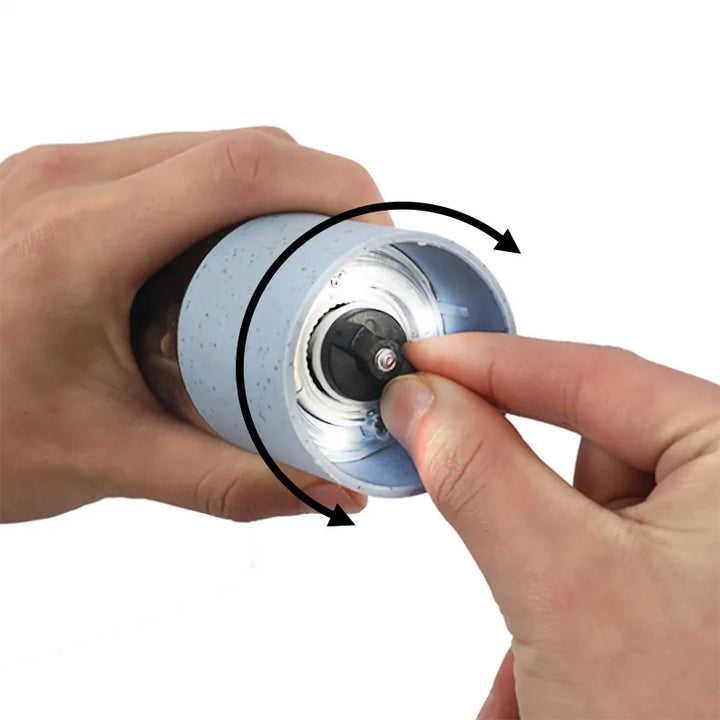 Hand hält blaue manuelle Kaffeemühle, Keramikmahlwerk, verstellbar, kompakt, tragbar.