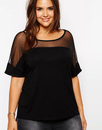 Frau in schwarzem T-Shirt mit transparenten Ärmeln, lächelnd, Plus-Size-Mode, Freizeitkleidung.