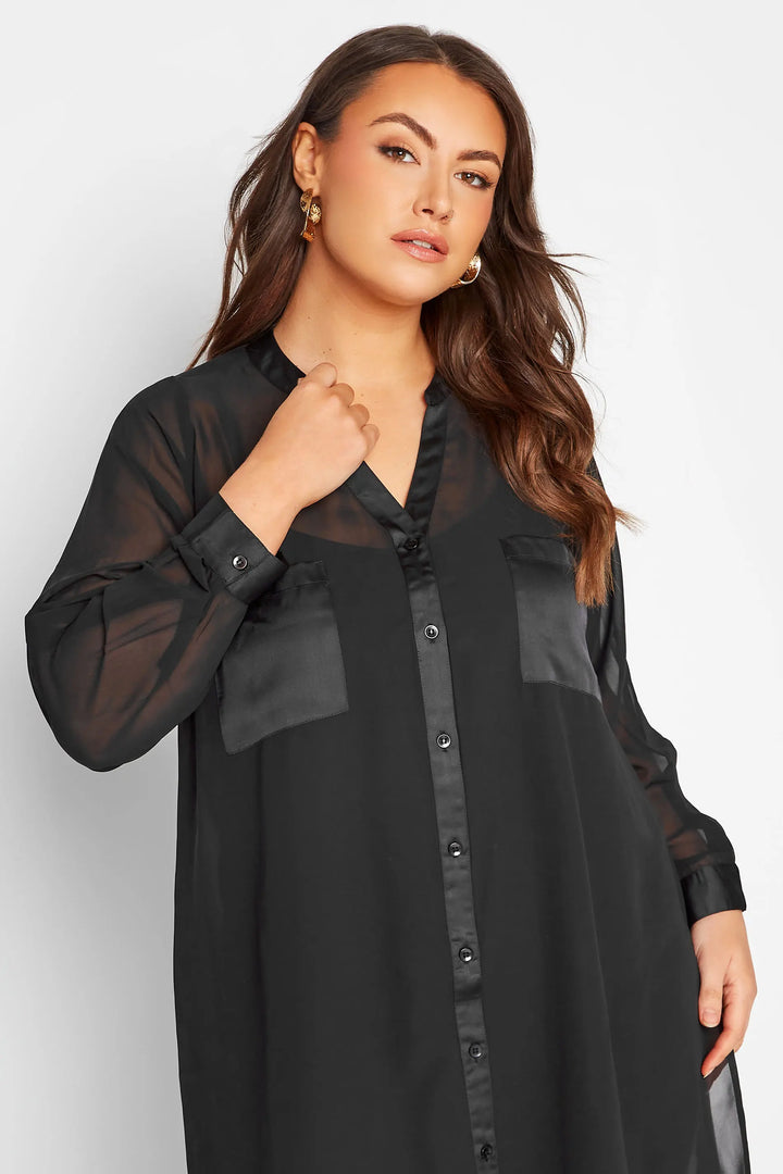 Frau in schwarzer, transparenter Bluse mit Knopfleiste und langen Ärmeln, elegant, modisch.