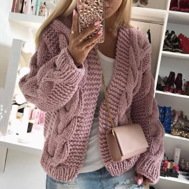 Frau in rosa Strickjacke, Handyhülle mit Muster, beige Umhängetasche, modische Kleidung.
