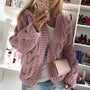 Frau in rosa Strickjacke, Handyhülle mit Muster, beige Umhängetasche, modische Kleidung.