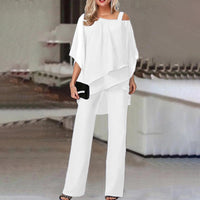 Frau in eleganter weißer Off-Shoulder-Bluse und Hose, Abendmode, schwarze Clutch.