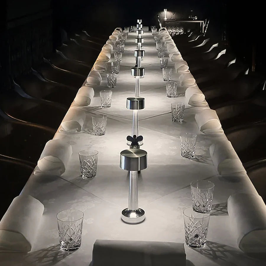 Langer, elegant gedeckter Tisch mit Kristallgläsern und modernen Salz- und Pfefferstreuern.