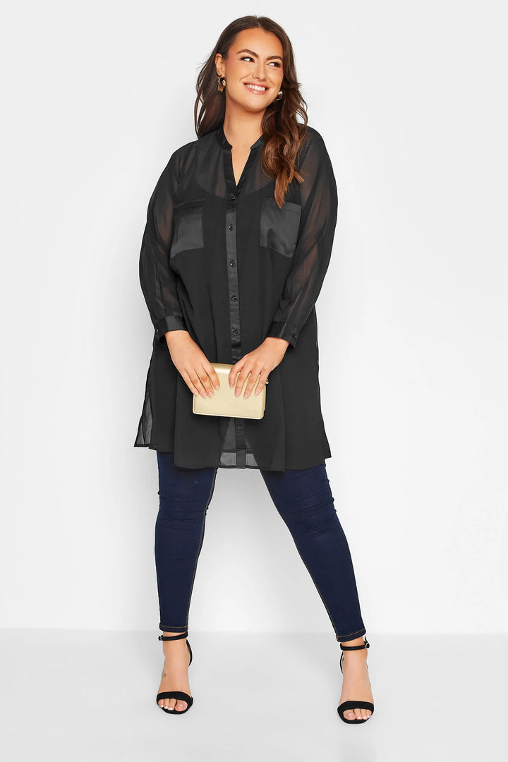 Frau in schwarzer Bluse und blauer Jeans, hält eine beige Clutch, lächelt, Modefotografie.