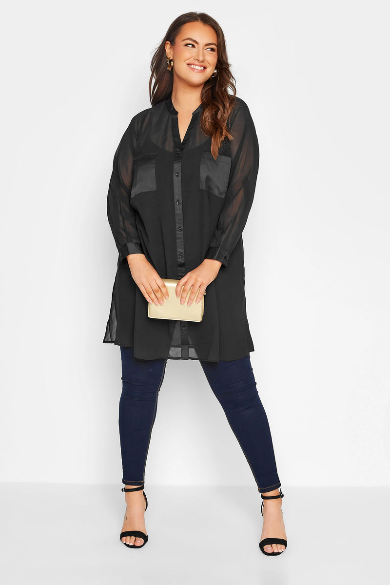 Frau in schwarzer Bluse und blauer Jeans, hält eine beige Clutch, lächelt, Modefotografie.