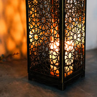 Orientalische Laterne aus Metall mit Kerzenlicht, dekorative marokkanische Lampe, warmes Ambiente.