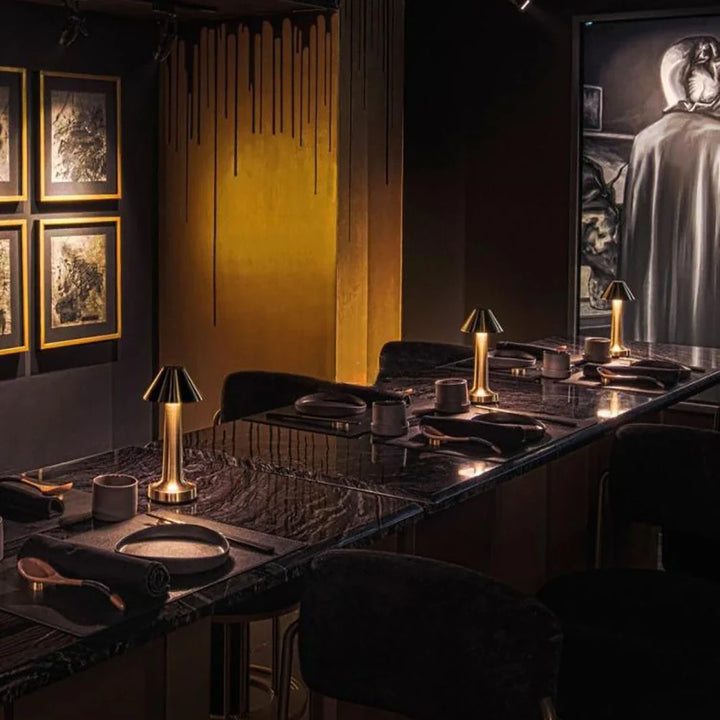 Luxuriöses Restaurant-Interieur mit dunklem Marmortisch, goldenen Lampen und stilvoller Dekoration.