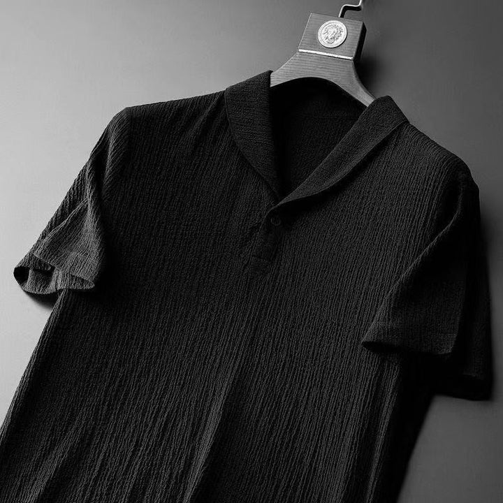 Schwarzes Herren-Poloshirt aus Baumwolle, kurzärmelig, strukturiert, elegant, auf Kleiderbügel.