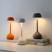 Moderne Tischlampen in Orange, Weiß und Grau auf Büchern, minimalistisches Design, LED-Beleuchtung.