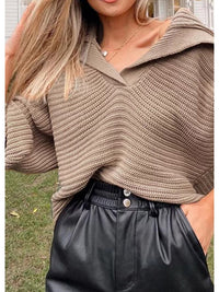 Frau in beigem Strickpullover und schwarzer Lederhose im Freien.