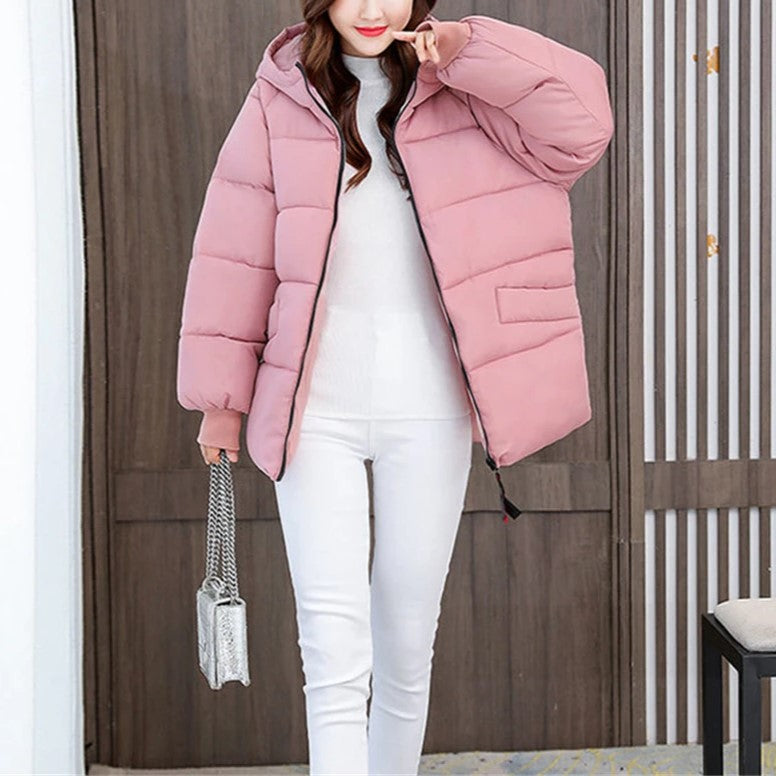 Frau in rosa Daunenjacke, weiße Hose, silberne Handtasche, Wintermode, stilvoll, warm.