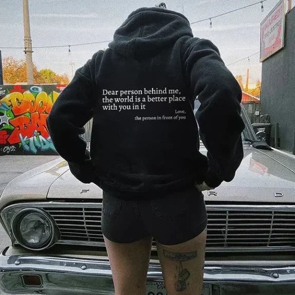 Schwarzer Hoodie mit weißem Text, Frau, Rückansicht, lässige Mode, urbaner Hintergrund.