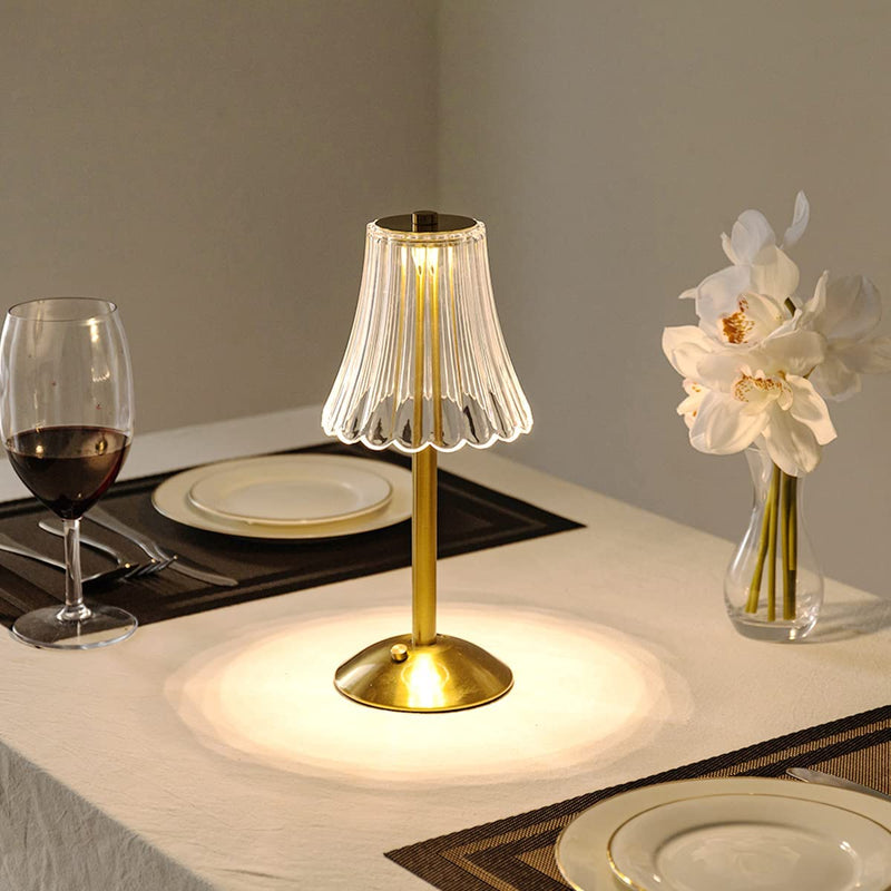 Goldene Tischlampe mit Glaslampenschirm auf gedecktem Tisch, elegante Beleuchtung, modern.