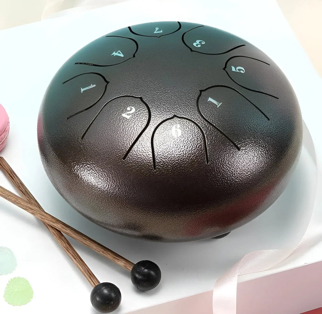 Schwarze Stahlzungentrommel mit Schlägeln, ideal für Meditation und Musiktherapie.