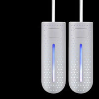 Zwei weiße elektrische Schuhwärmer mit LED-Anzeige auf schwarzem Hintergrund.