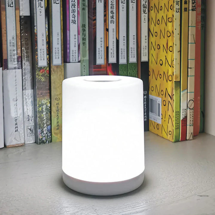 LED-Tischlampe mit stufenloser Dimmung, Touch-Steuerung, USB-aufladbar, weiß, vor Bücherregal.