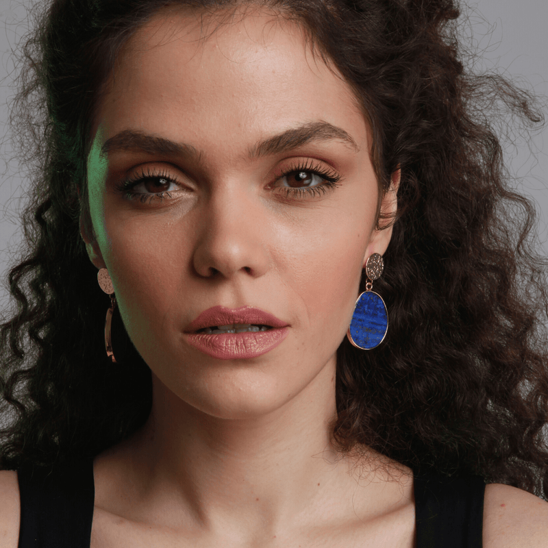 Frau mit blauen Ohrringen, lockigem Haar, schwarzem Top, Nahaufnahme, Modeaccessoire.