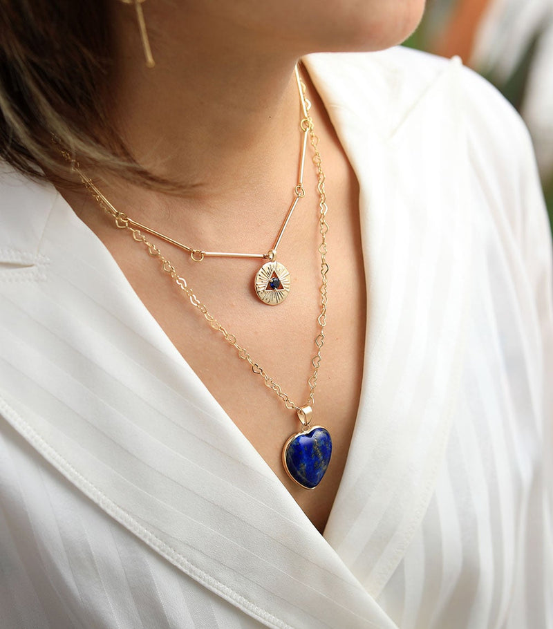Frau mit goldener Halskette, Lapis-Lazuli-Herzanhänger, modisches Schmuckdesign.