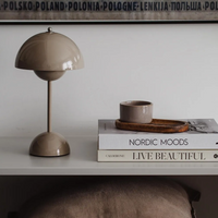 Beige Tischlampe auf weißem Regal mit Büchern und Tasse, skandinavisches Design, Wohnzimmer-Dekor.