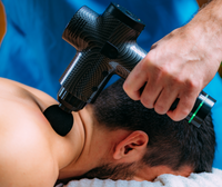 Mann erhält Massage mit schwarzer Massagepistole aus Carbon, Muskelentspannung, Therapie.